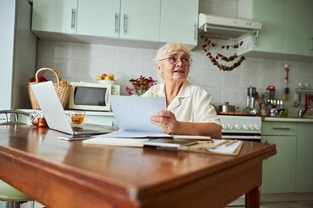 A smiling elderly woman is reviewing documents at her kitchen table. She is surrounded by papers, including a utility bill and benefit application form; this is to create a positive feeling of solving a problem.